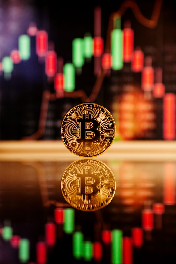 ours-journey Golden Bitcoin standing in front of a financial chart, reflecting the cryptocurrency market volatility.